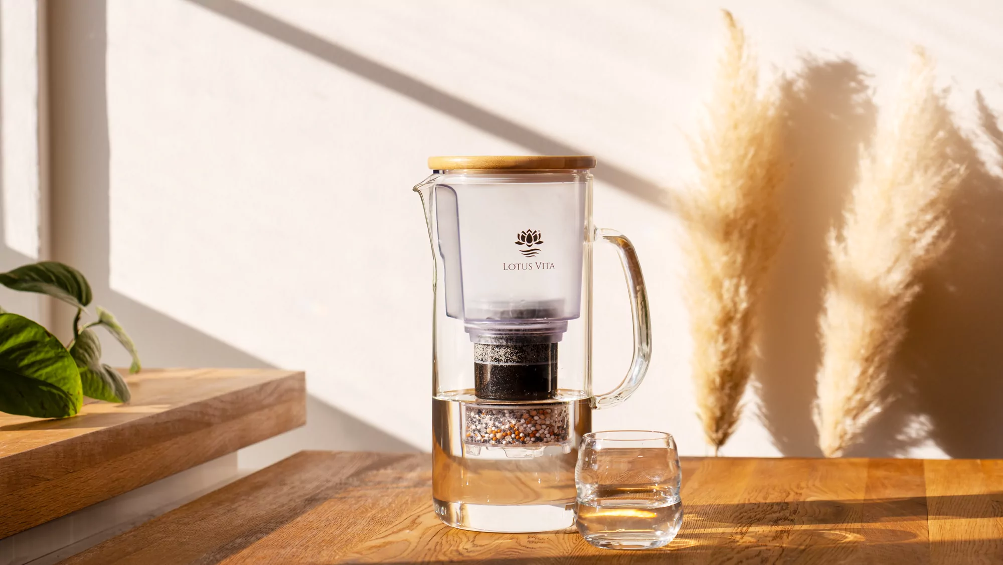 Clear water pouring into a glass beside the Lotus Vita ENYA carafe